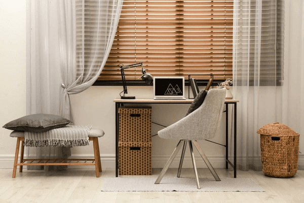 A stylish home office in Dubai featuring wooden blinds, a modern desk, a cozy chair, and elegant décor. The roman blind 2025 best and cheap adds warmth and functionality.
