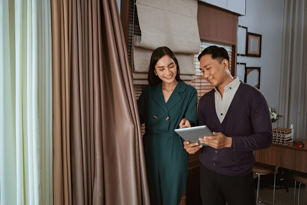 Female staff member at Emirati Blinds & Curtains showcasing curtain ranges to a satisfied client in Dubai.