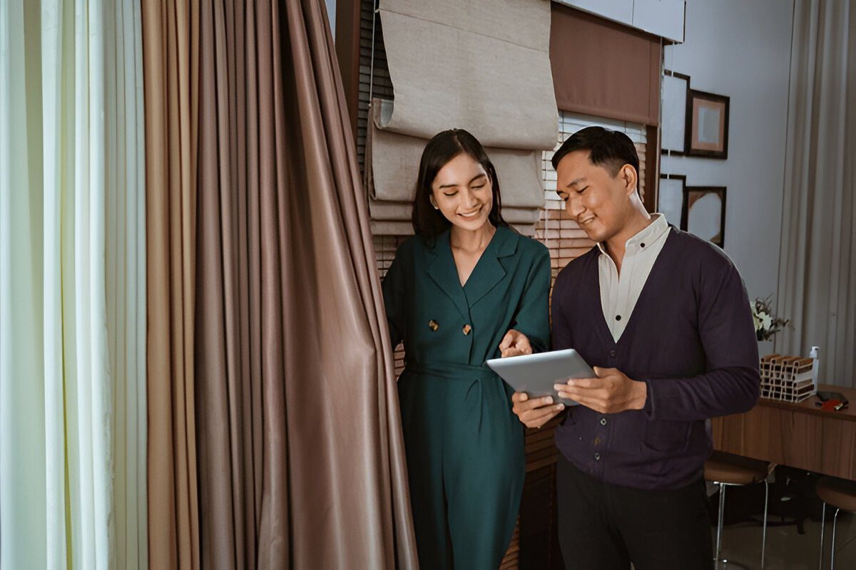 Female staff member at Emirati Blinds & Curtains showcasing curtain ranges to a satisfied client in Dubai.