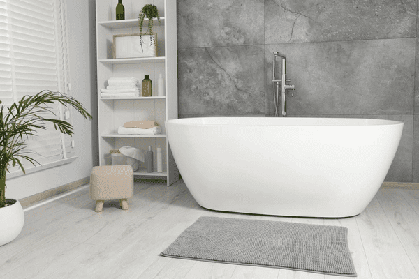 A sleek and modern bathroom featuring a white freestanding bathtub, minimalist décor, and elegant white window blinds, showcasing the best and most affordable window blinds in Dubai for 2025.