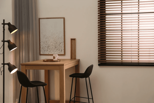  Modern dining corner with wooden Venetian blinds, warm lighting, and minimalist décor for a cozy and elegant ambiance.
