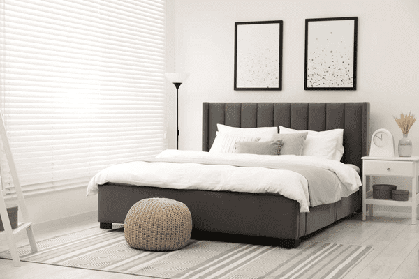 A modern bedroom featuring sleek white blinds, a plush gray bed, and minimalist decor, creating a luxurious and stylish ambiance in Dubai 2025.