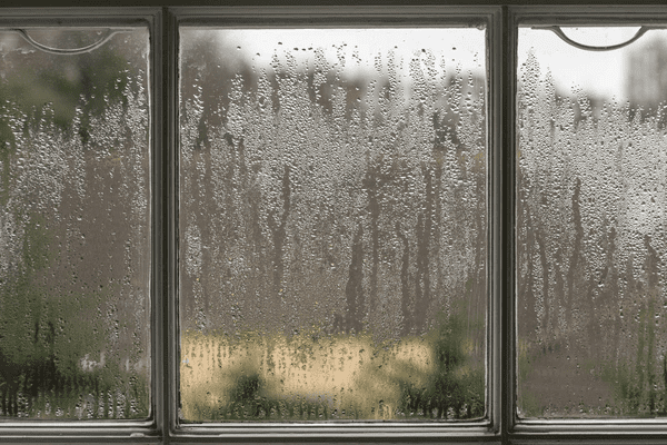 Close-up of a glass window covered in heavy condensation, illustrating the importance of moisture-resistant roman blinds in Dubai 2025 homes.