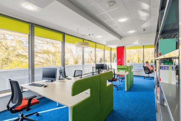 A bright and colorful office space with green and yellow window blinds, designed to reduce glare and enhance productivity.