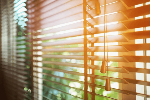 Close-up of elegant wooden window blinds with sunlight streaming through, showcasing a modern and trendy design ideal for reducing heat in Dubai homes.