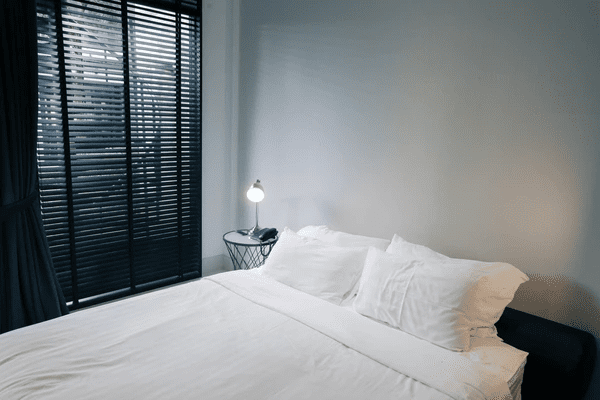 A modern bedroom with black window blinds, offering privacy, sunlight control, and eye strain reduction in a Dubai home.

