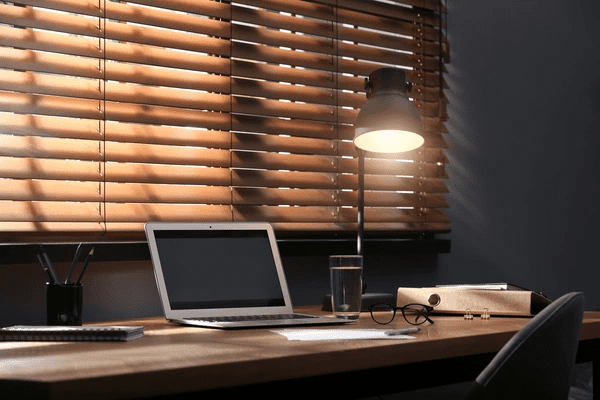 A cozy and modern workspace with wooden blinds filtering soft light, creating a warm and professional atmosphere.