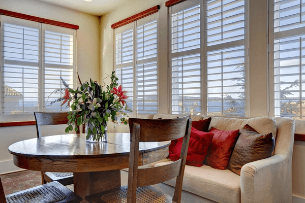 A beautifully designed dining area featuring large windows with sleek white plantation shutters, offering a blend of natural light, privacy, and a modern aesthetic.