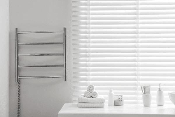 A stylish white bathroom featuring sleek white cut-size blinds, a heated towel rail, and neatly arranged towels and toiletries, creating a modern and luxurious ambiance in Dubai 2025.