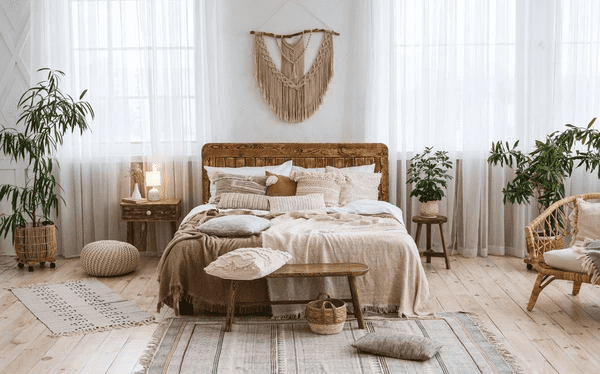 A stunning bohemian-style bedroom featuring modern sheer white curtains, a rustic wooden bed, cozy neutral bedding, and lush green plants, creating a warm and inviting ambiance.