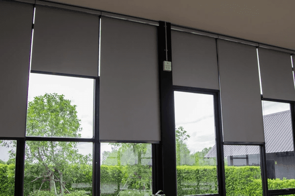 Sleek gray window roller blinds covering large glass windows in a modern home, offering privacy and light control.
