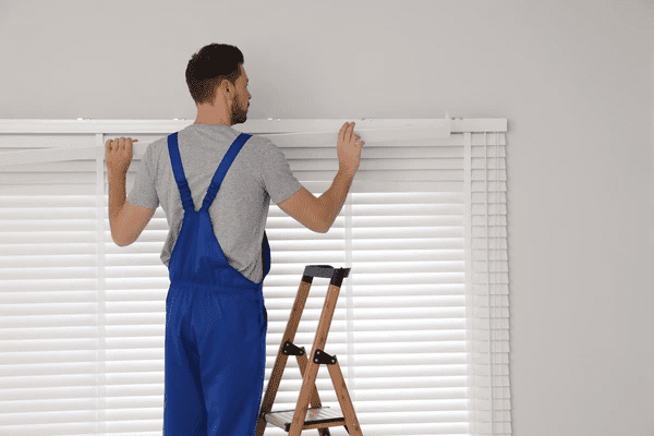 A professional installer from Emirati Blinds & Curtains fixing roller blinds in Dubai 2025.