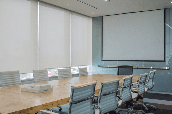 A modern Dubai office meeting room with white roller blinds, ensuring reduced distractions, enhanced privacy, and improved productivity.
