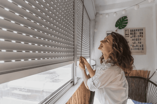 A woman adjusting high-quality roman blinds 2025 for privacy and sun protection in a stylish Dubai home.
