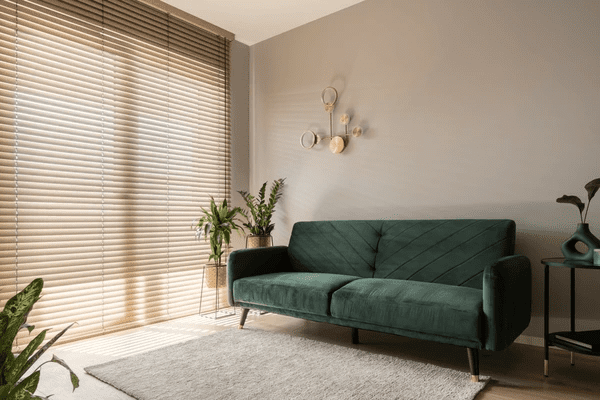 A stylish living room featuring sleek wooden soundproofing blinds, a luxurious dark green sofa, and elegant décor, creating a cozy and noise-free ambiance.