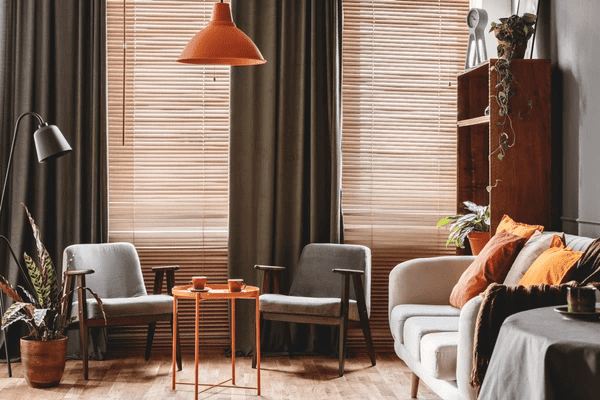 Stylish living room featuring wooden blinds and dark curtains, showcasing the best blinds & curtains in Dubai 2025 for a warm and elegant ambiance.