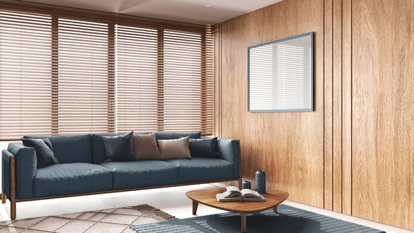 A stylish Japandi-style living room featuring sleek wooden blinds, a deep blue sofa, and a modern minimalist aesthetic, showcasing how blinds enhance elegance and functionality better than curtains.