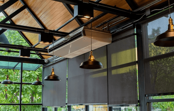 Industrial-style space with blackout roller blinds 2025 best and cheap in Dubai, featuring pendant lights and large glass windows.