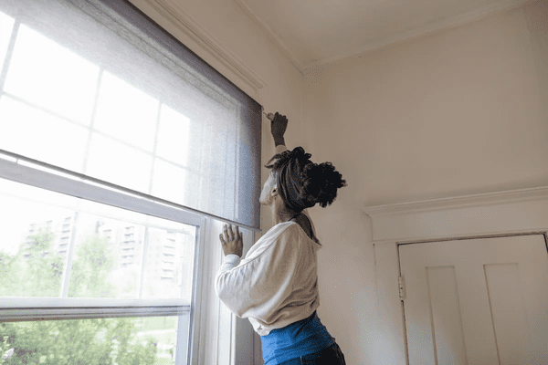 A woman measuring her window for DIY blinds installation, following a top-rated beginner guide for achieving the perfect fit for blinds in Dubai 2025 best options.