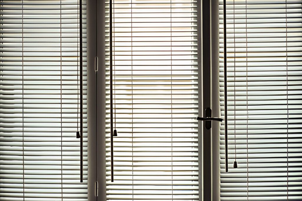 Elegant horizontal blinds covering glass doors and windows, filtering sunlight while maintaining privacy. These best Roman blinds Dubai 2025 blend traditional Emirati cultural aesthetics with modern functionality, offering a stylish and practical home décor solution.