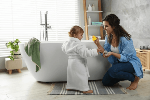 A stylish bathroom featuring modern white blinds, a freestanding bathtub, and a mother playing with her child in a cozy setting.