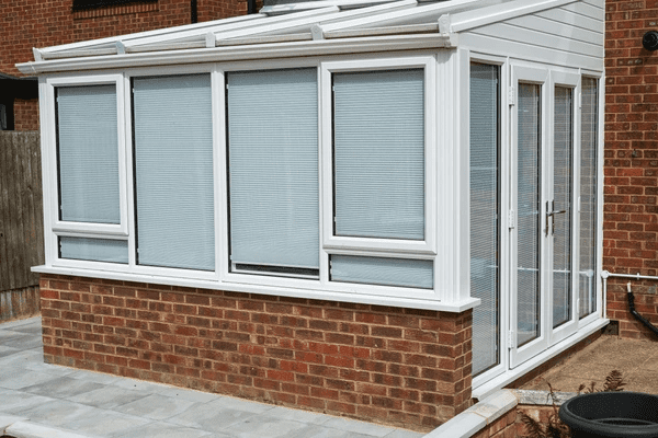White conservatory with sleek fitted blinds on all windows, offering a modern and private look.