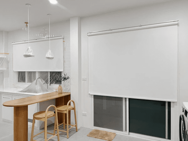 Best Long Blinds in Dubai 2025 - A modern kitchen features sleek white roller blinds covering a large window, offering elegance and functionality