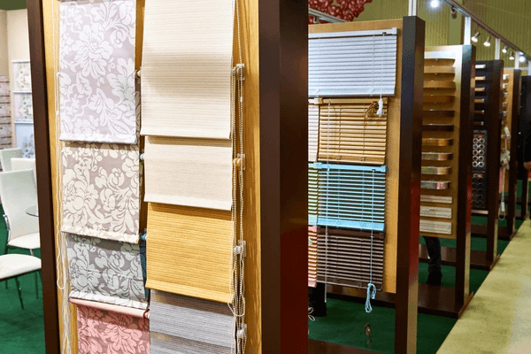 A display of various cheap and discounted blinds in a Dubai store, including fabric, bamboo, and roller blind samples.