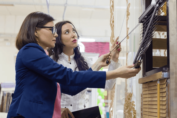 Two women examining sleek and elegant discounted blinds in a modern Dubai home décor store in 2025.