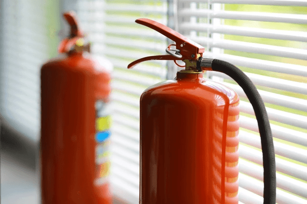 Close-up of fire extinguishers placed near window blinds for enhanced fire safety in modern Dubai homes.