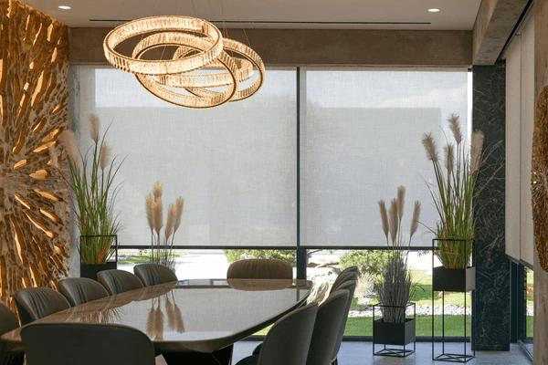 Trendy dining room in Dubai featuring sleek fire resistant roller blinds, luxury lighting, and cozy modern decor.