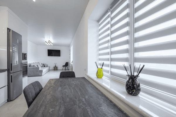 Modern Dubai dining area with stylish fire resistant zebra blinds on white-framed windows and minimalistic decor.