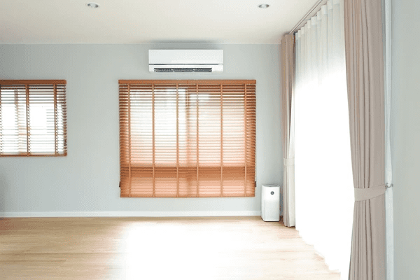 Bright living room featuring wooden blinds on windows with soft pink curtains for a modern cozy vibe.