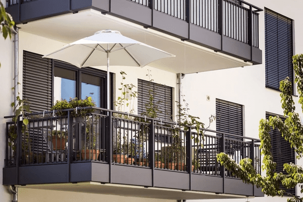 Stylish apartment balcony with sleek black outdoor blinds, potted plants, and a white umbrella—ideal for elegant and cozy Dubai homes in 2025.