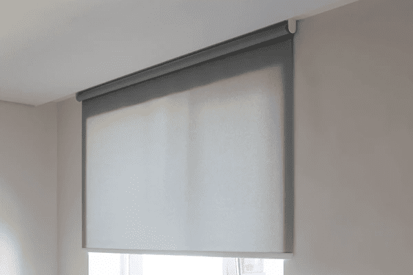 Close-up of a grey painted roller blind installed on a window in a minimalistic room with soft natural light.