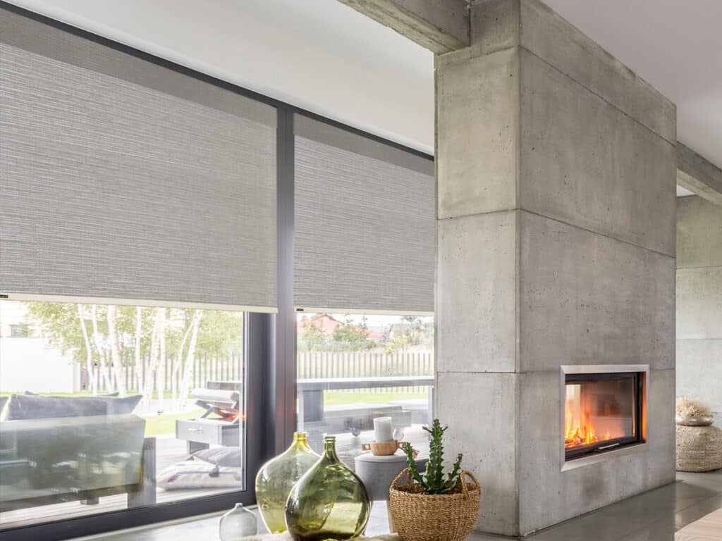 Contemporary roller shades covering large patio glass doors in a modern living room with a fireplace.