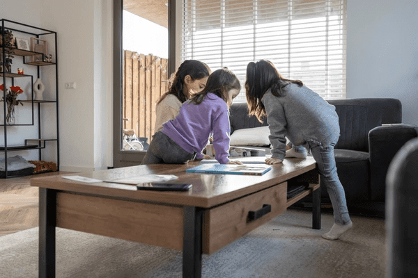 A cozy family living room with modern wooden blinds, a mother and two children engaging in an activity around a wooden coffee table.