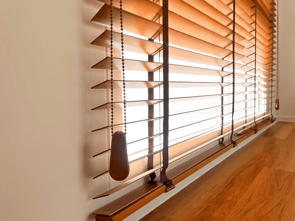 Elegant brown recycled wooden blinds partially open with natural light filtering through.