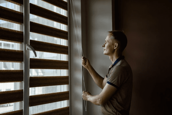 Man pulling the cord of modern roller blinds in a stylish, cozy room in Dubai 2025