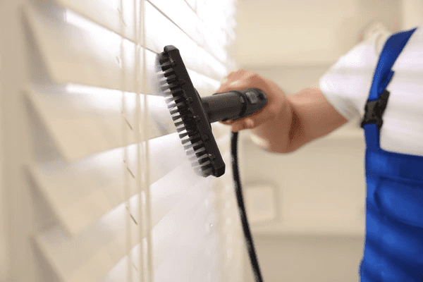 Professional cleaner steam washing white blinds in a modern home interior in Dubai 2025.