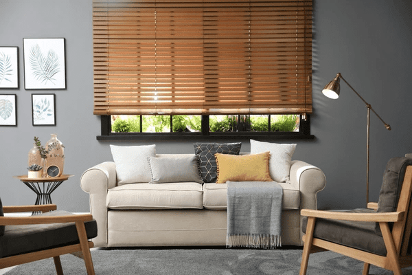 A modern living room featuring elegant wooden blinds, a plush beige sofa, and stylish décor for a cozy ambiance.