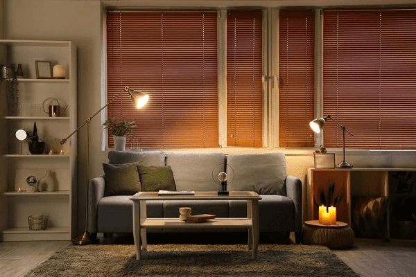 A stylish modern living room with warm wooden blinds, soft lighting, and a cozy seating area with decorative elements.