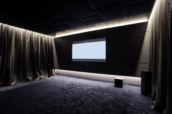 Dark home theater room with luxurious blackout curtains, a blank projector screen, and a plush carpeted floor.