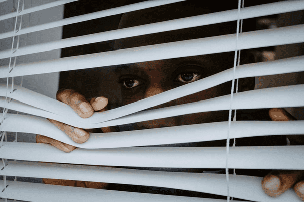 Man peeking through premium capital improvement grade window blinds in a modern Dubai home