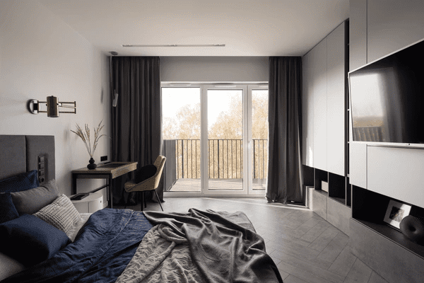 Contemporary Dubai bedroom with sleek blackout curtains designed to retain heat, dark-toned bedding, and minimalist furniture.