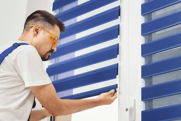 Technician installing blue zebra blinds on a window, showcasing easy-to-install blind solutions for modern Dubai homes.