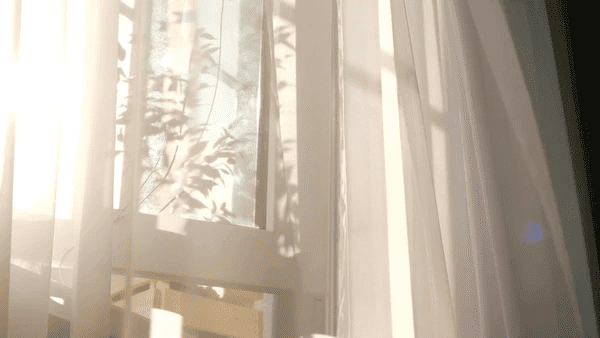 Soft, light-colored curtains allowing gentle sunlight to filter through, showcasing superior heat-insulation properties.