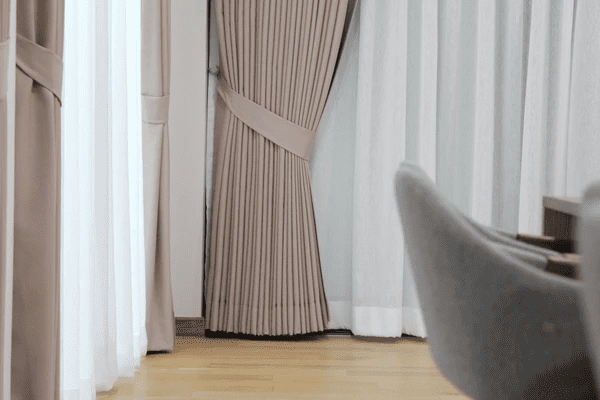 Close-up of beige layered curtains with tiebacks and sheer white drapes, designed for noise reduction in a modern Dubai home.