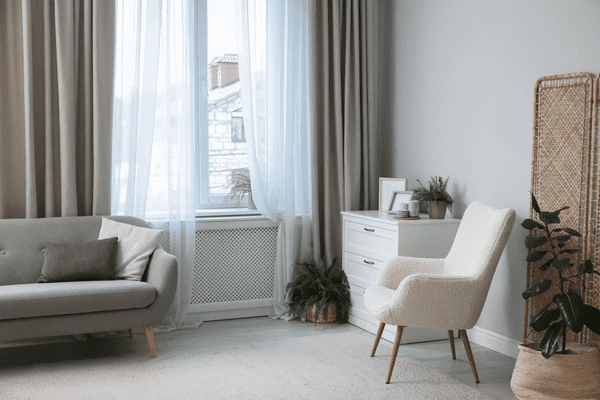 Bright and modern living room in Dubai featuring popular used beige curtains paired with sheer white drapes and minimalist furniture.