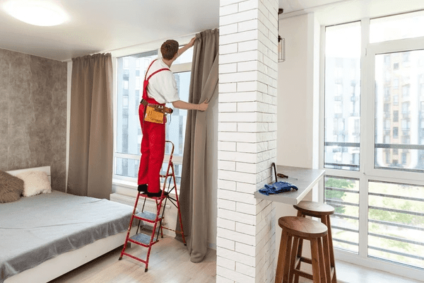 Installer measuring and fitting soundproof curtains in a contemporary living space, ensuring precise and stylish results.